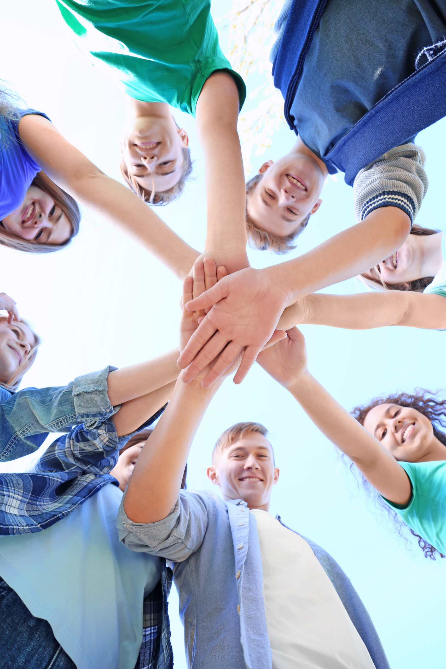 Young people putting hands together outdoors. Volunteering concept